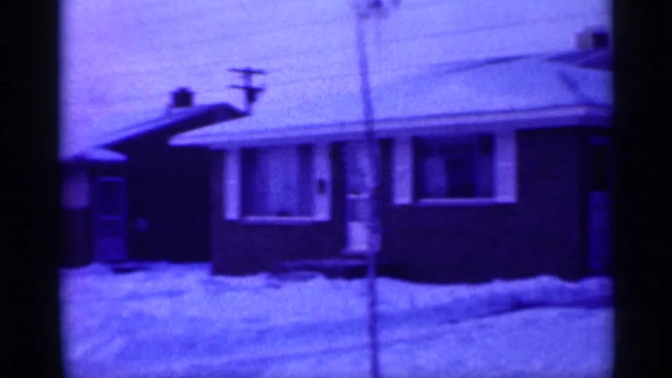 Close view of a snow-covered suburban home exterior in New Jersey, with a front window, porch area, utility pole, and roofline.