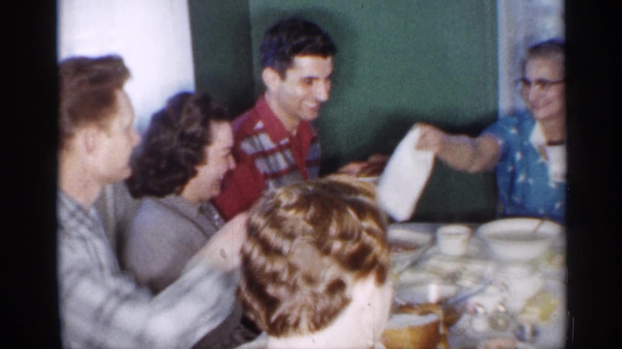 Several relatives sit close together at a table as a napkin is handed across the group.