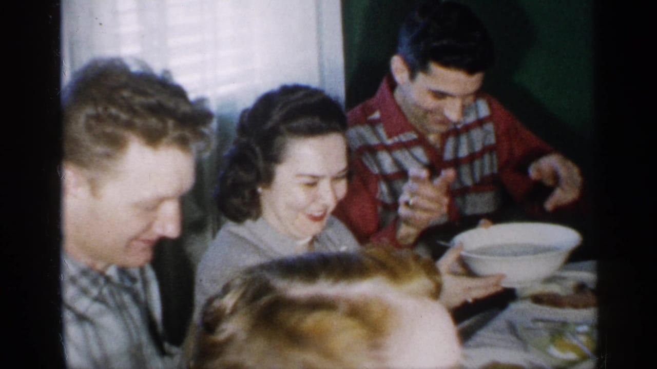 Adults seated closely around a dining table with a serving bowl.