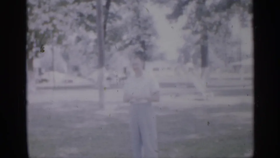 The final frame holds on the man in light clothing amid grass and trees, with the soft focus of 1958 8mm home-movie footage.