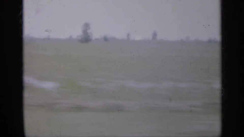 1958 New Jersey home-movie frame showing blurred fields and a low rural horizon through a dark vehicle-window divider.