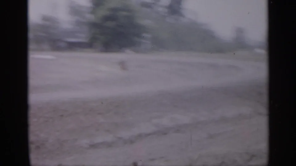 1958 New Jersey 8mm frame with a soft view across open ground toward a distant tree line and possible road surface.