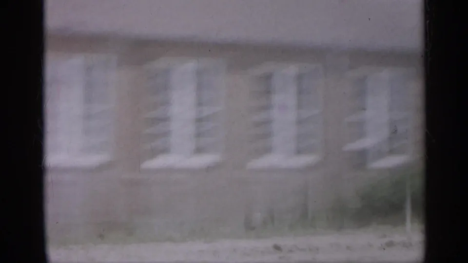 1958 New Jersey frame with a blurred brick facade and repeated white windows as the camera moves past.