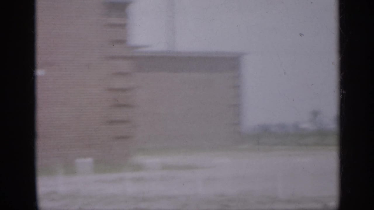Soft view of a brick building facade seen through dark window-frame divisions.