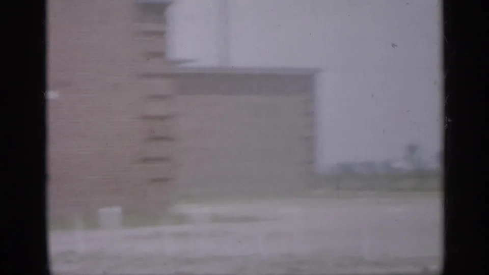 1958 New Jersey 8mm frame showing a hazy brick building exterior behind dark vertical window framing.
