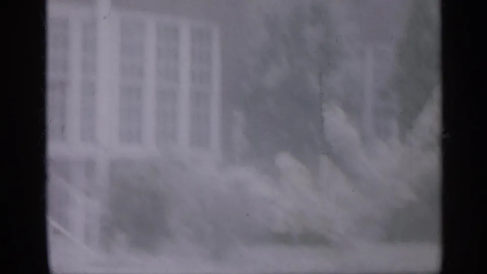 Soft 8mm view of a New Jersey building exterior with windows, railings, and nearby shrubs.