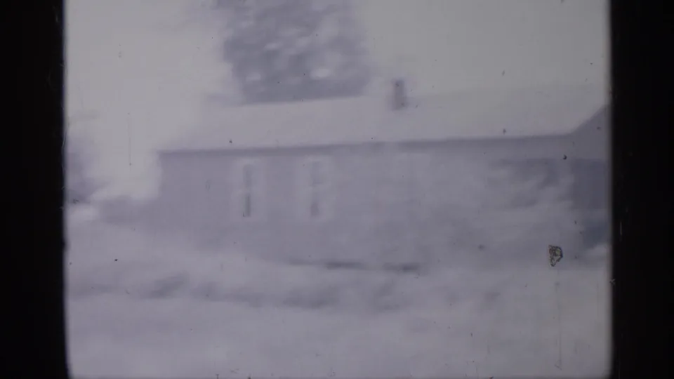 Overexposed 1958 New Jersey 8mm frame with a blurred side view of a light-colored house, windows, yard, and film border.