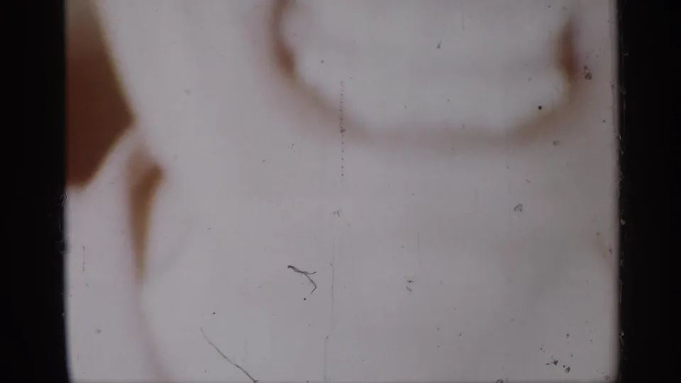 Soft 8mm close-up from the 1958 New Jersey home movie, showing part of a smiling face in very shallow focus.