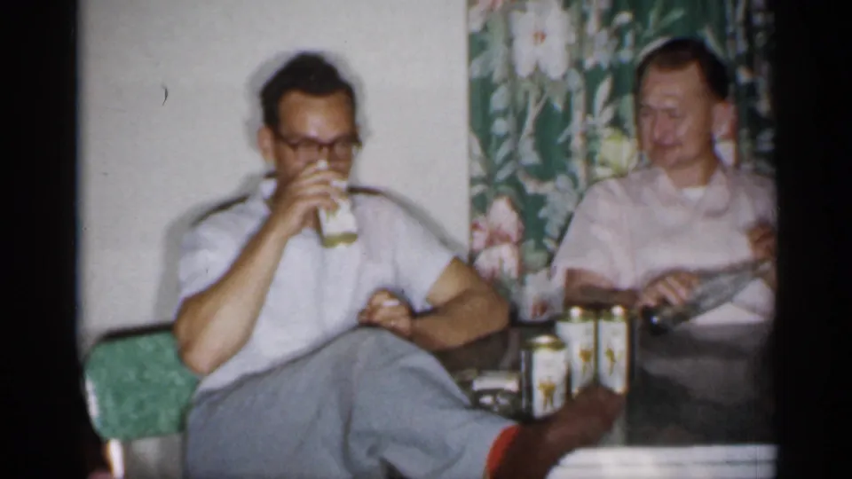 1958 New Jersey kitchen scene with one man drinking from a glass and another seated at the table beside cans.