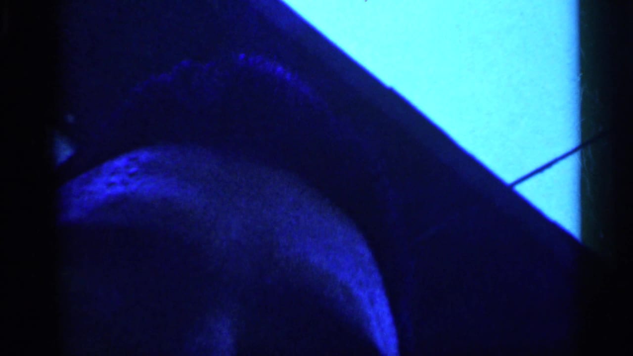 1958 New Jersey home-movie frame with a blue-lit partial head or face cropped tightly along the left side.