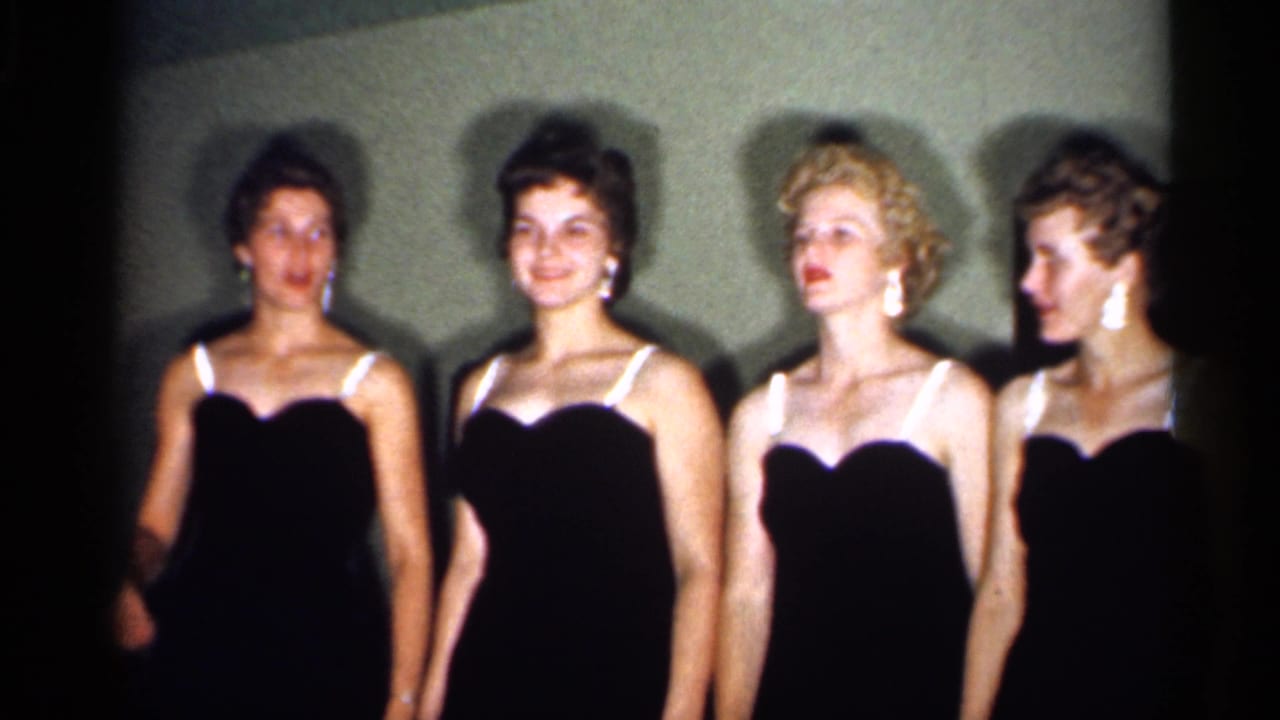 Four adult women in coordinated black dresses stand close together, with one looking sideways in the 1958 New Jersey clip.