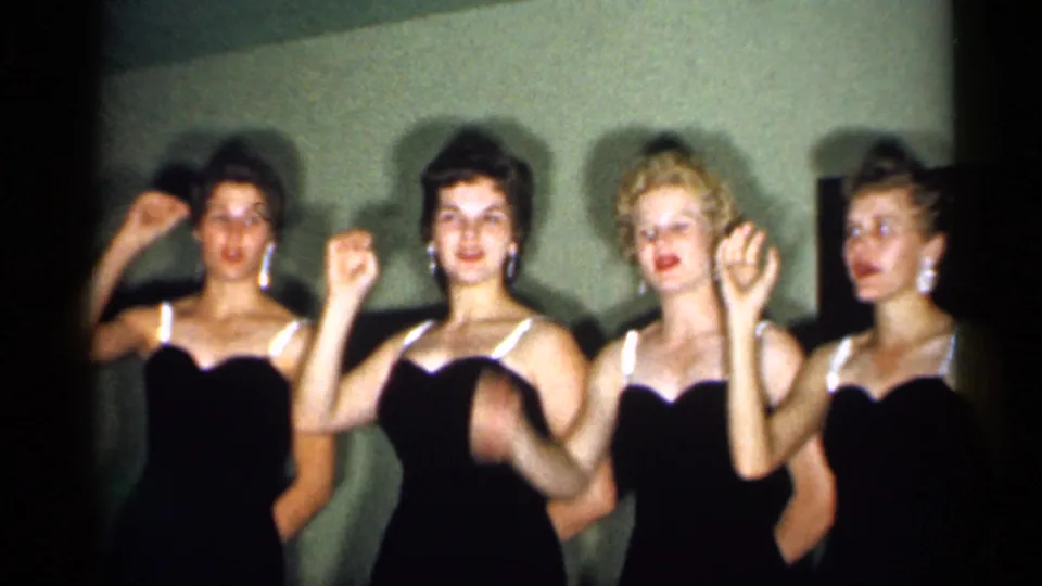 Four adult women continue the coordinated hand movement, framed closely in warm 8mm footage from New Jersey in 1958.