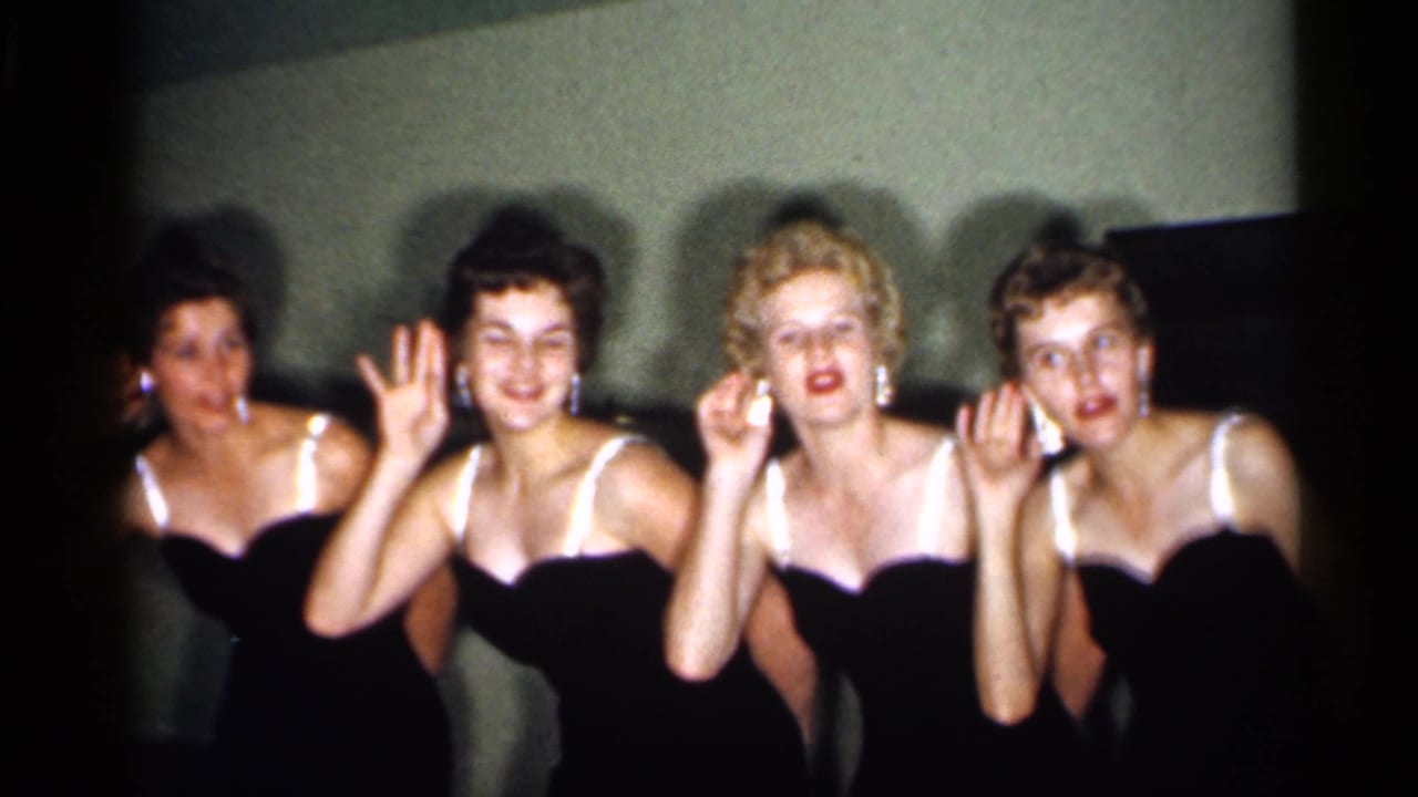 Four women in black gowns make playful raised-hand gestures during a 1958 New Jersey home-movie routine.