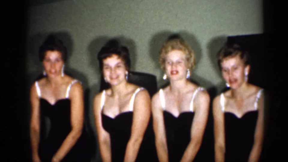 Four young women in matching dark dresses with white trim pose indoors in 1958 New Jersey home-movie footage.