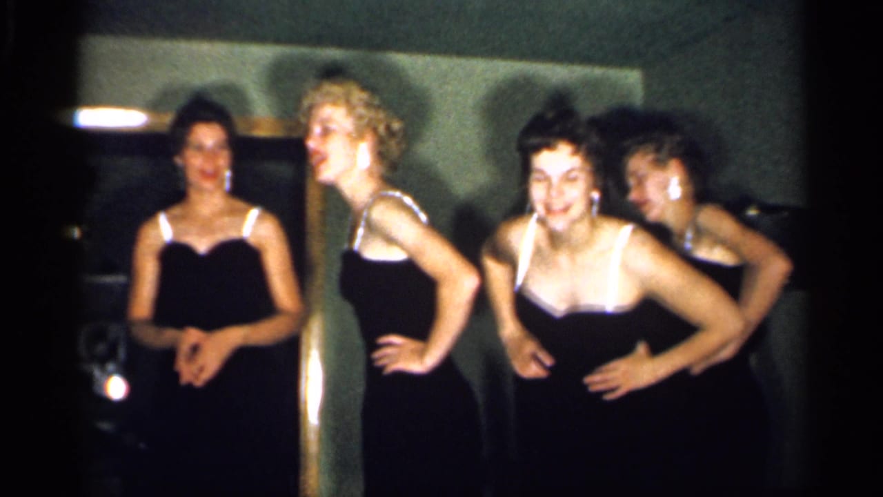 Four adult women in black dresses pose with hands at their waists inside a private-looking New Jersey interior from 1958.