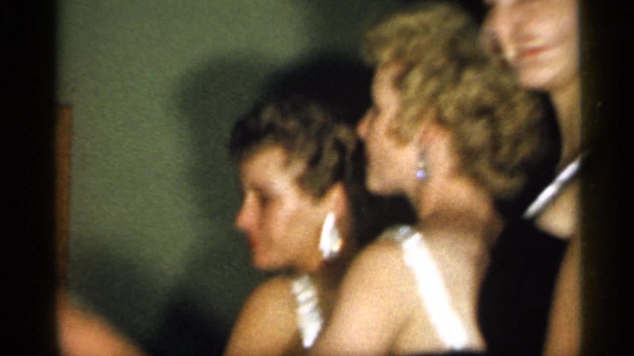 Young women in black dresses and jewelry appear in profile during a 1958 New Jersey indoor social gathering.