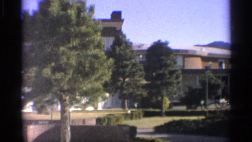 The motel exterior appears behind trees, with landscaped grounds and an Arizona mountain ridge in the distance.