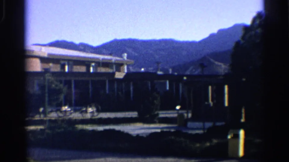 The final frame holds a wider 1959 Arizona view of the motel grounds set against a dark mountain ridge.