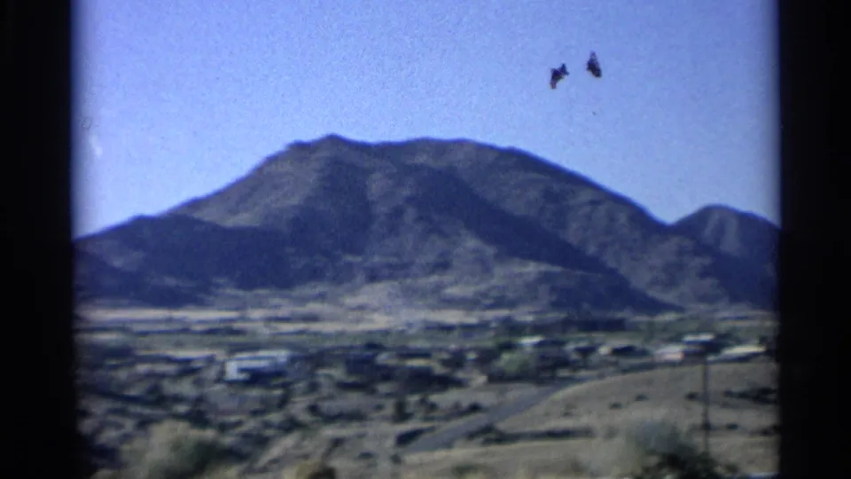 1959 Arizona frame showing a mountain above a wide desert town view, with road edges and small structures below.