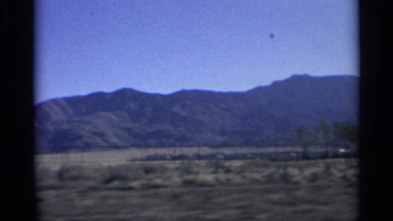 Mountain ridge and arid roadside landscape beneath a clear blue sky.