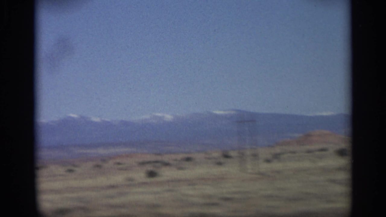 Desert plain with distant mountains and a utility pole near the right side.