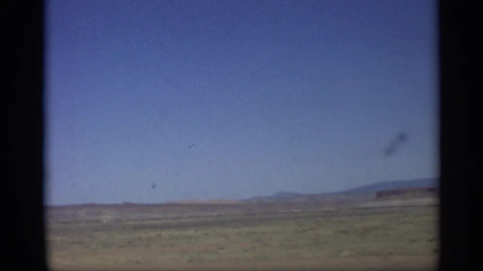 1959 Arizona desert horizon with open sky and a small aircraft-like shape crossing the upper right of the frame.