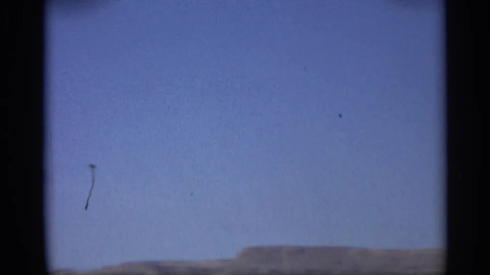 1959 Arizona 8mm frame dominated by blue sky, with a low desert horizon and visible film dust near the frame edge.