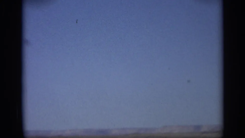 1959 Arizona 8mm frame showing a broad blue sky above distant low desert hills, with the landscape low in the frame.
