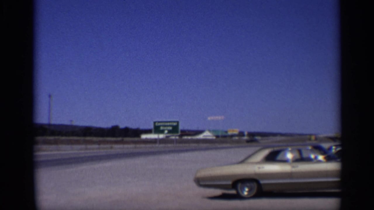 Gold car on a highway shoulder with a green Continental Divide sign in the distance.