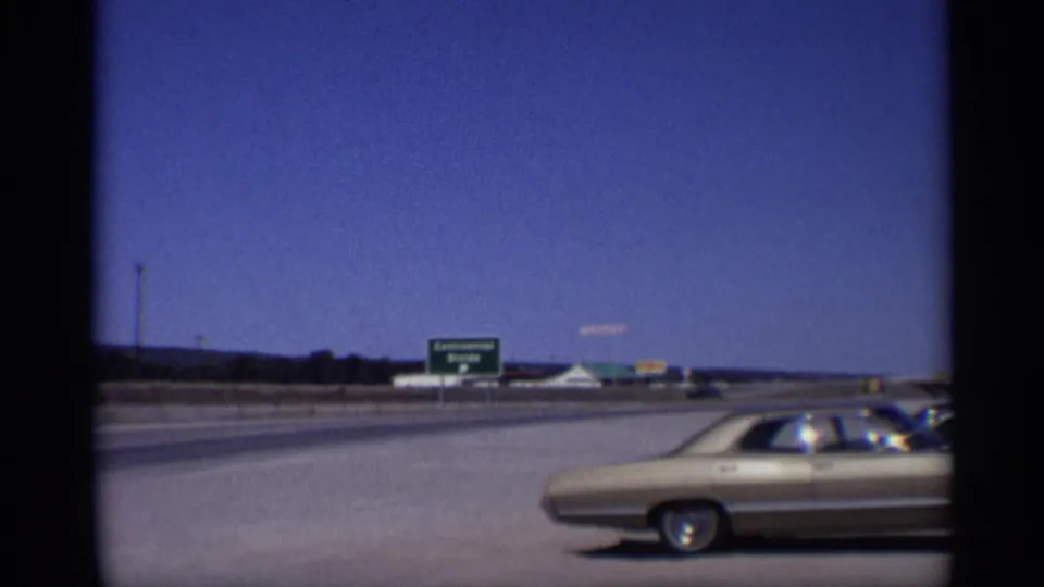 1959 Arizona highway view with a gold car in the foreground and a green Continental Divide sign across the road.