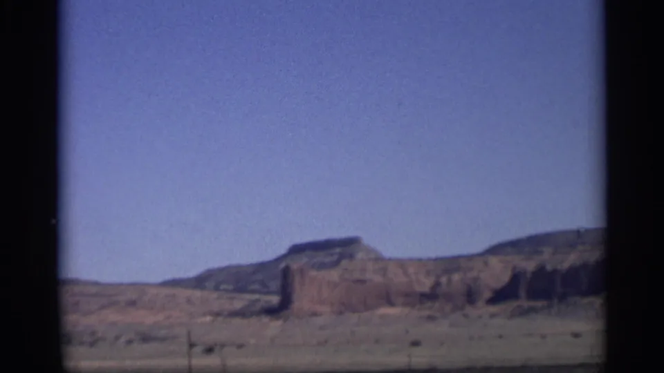 1959 Arizona road-view frame with layered mesa formations stretching across an open desert horizon.