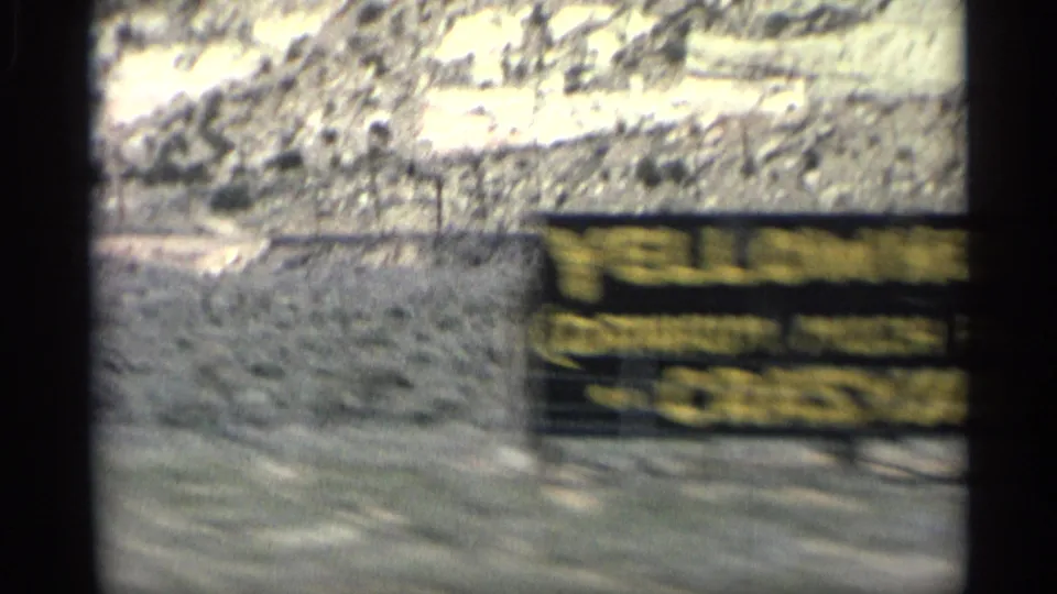 1959 Arizona 8mm frame showing a yellow roadside sign reading Yellowhorse and Crazyhorse beside arid hills.