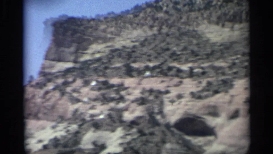 Arizona desert slope and scrub brush fill the 1959 8mm frame as the car moves past the terrain.