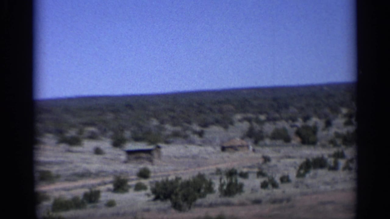 Small roadside structures in a dry desert landscape under blue sky.