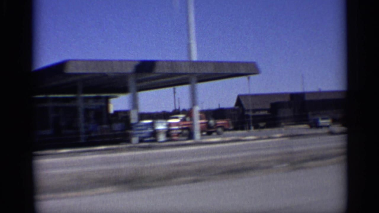 Roadside canopy with parked cars and low buildings beyond the street.