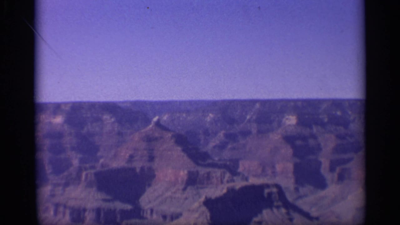 Wide canyon view under a clear sky with a purple color cast.