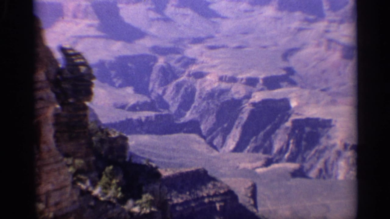 Aerial view of Grand Canyon cliffs and ravines with dark film borders.