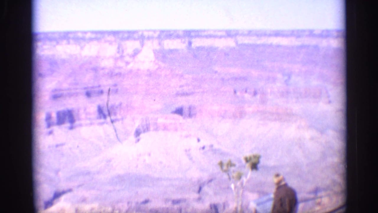 Soft 8mm frame of the Grand Canyon with a visitor near an overlook railing.
