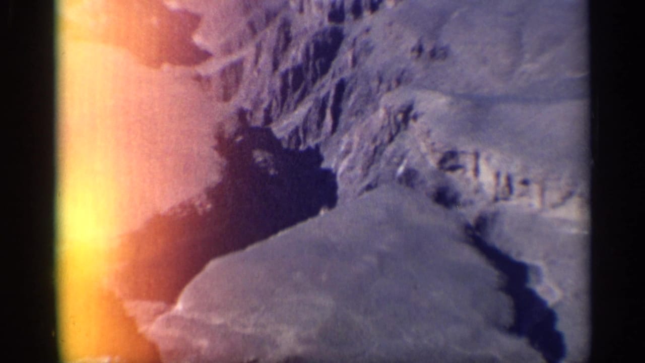 Rugged canyon walls and a dark ravine with strong orange light flare at the frame edge.