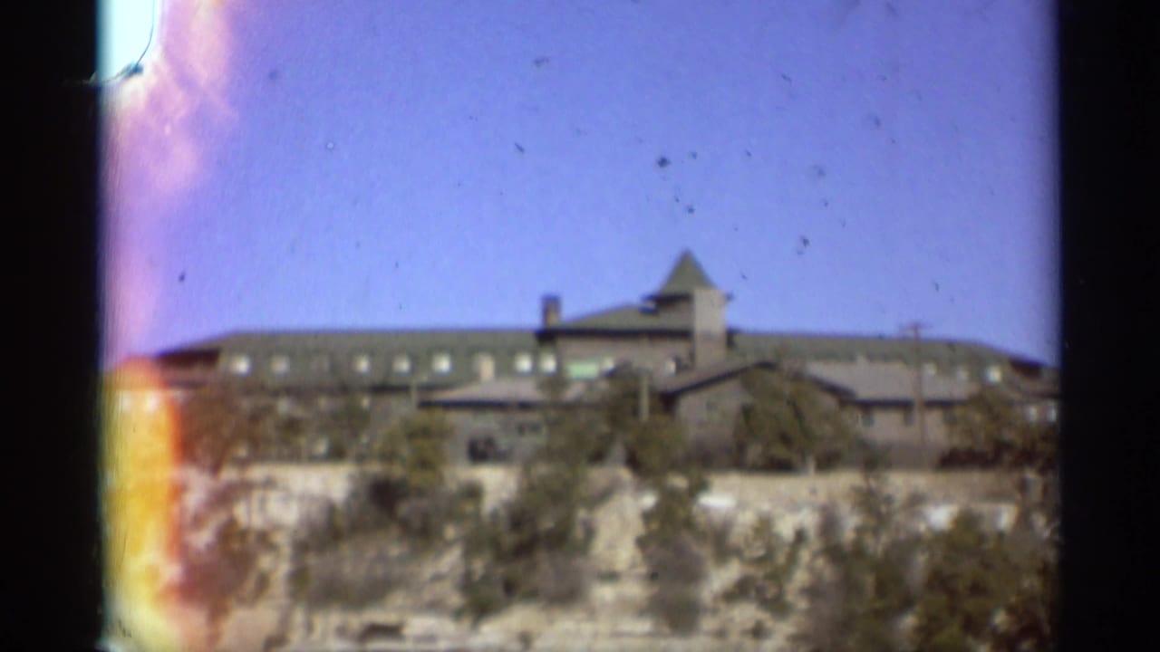 Large building on a rocky canyon rim under blue sky.