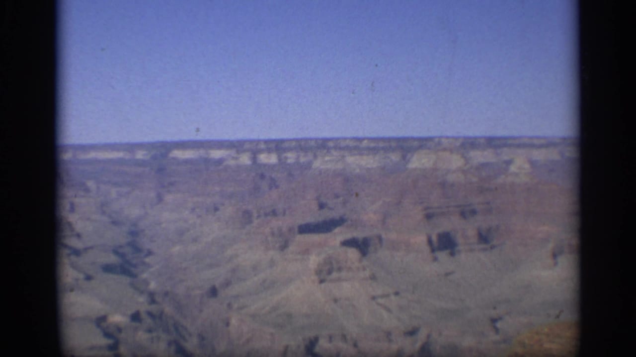 Distant Grand Canyon view with blue sky and layered canyon walls.
