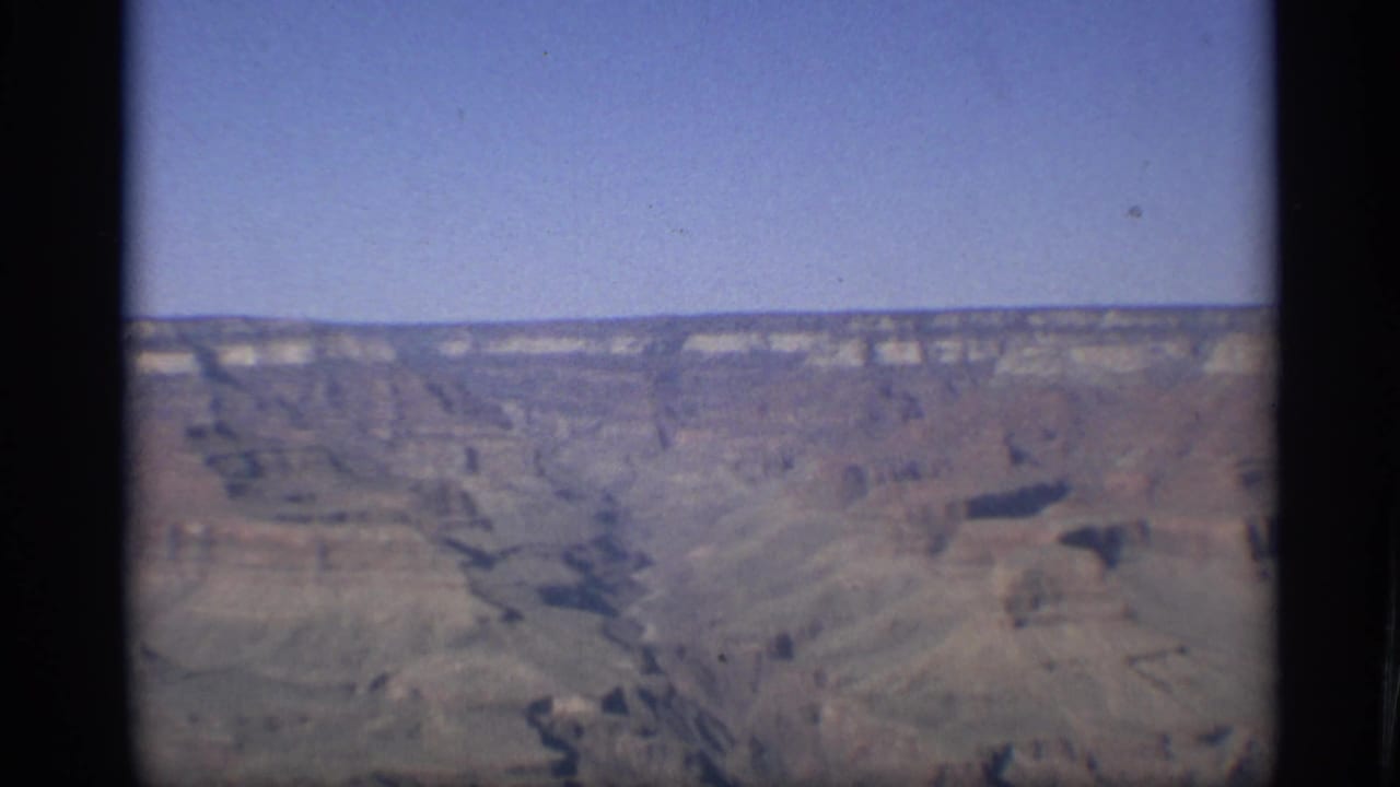Grand Canyon rock formations and deep ravines under clear sky.