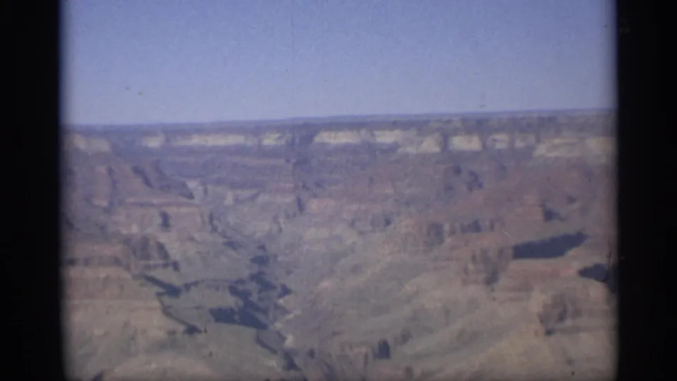 A wide 8mm view of the Grand Canyon in Arizona shows the horizon line, pale cliffs, and dark cuts through the landscape.