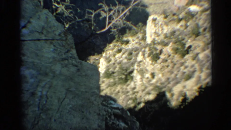 Vintage Arizona hillside view with pale rock, sparse brush, and deep shadow across the lower frame.