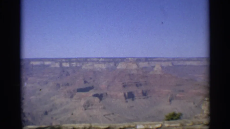 1959 Arizona 8mm frame of the Grand Canyon landscape, with layered formations across the horizon and a dark vertical film border.