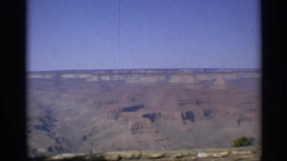1959 Arizona home-movie frame showing a canyon vista beyond a low stone railing, with soft focus and faded 8mm color.