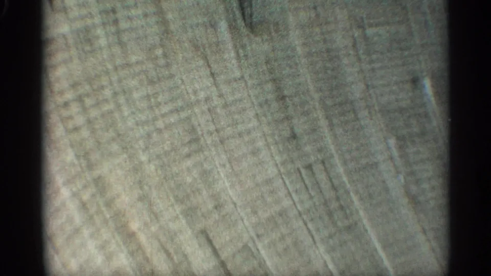 A close view shows the textured concrete surface of the dam wall, emphasizing scale through diagonal seams and weathered tonal variation.