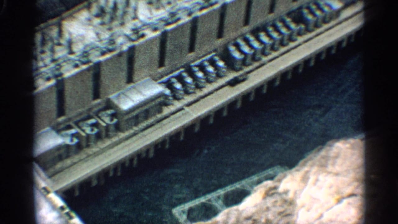Dam structure beside dark water with equipment lined along a long deck.