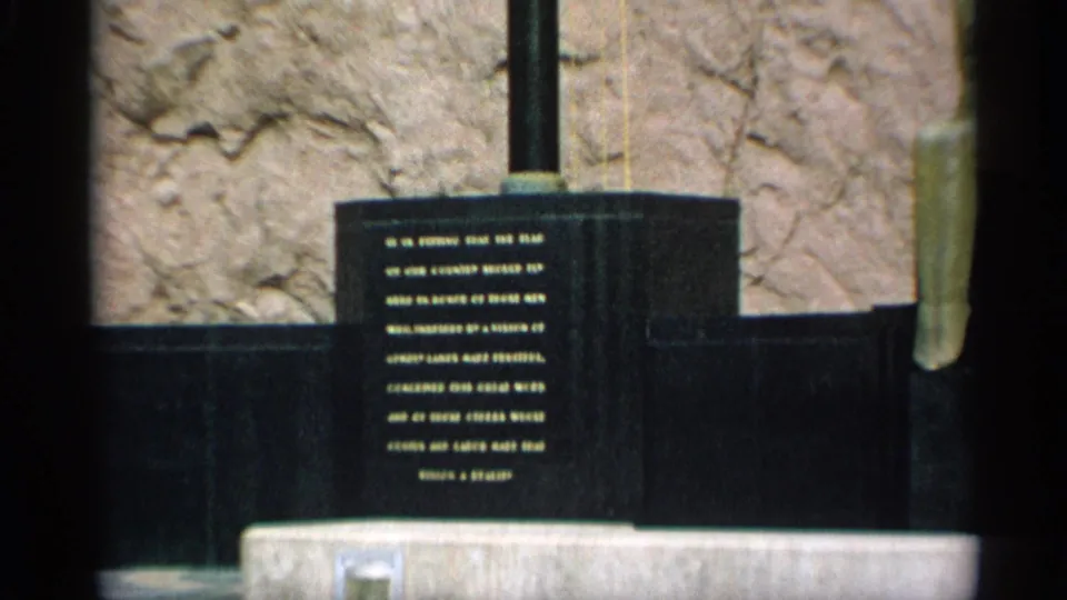 1959 Arizona 8mm frame showing a dark commemorative monument or plaque with engraved text, partly soft and difficult to read.