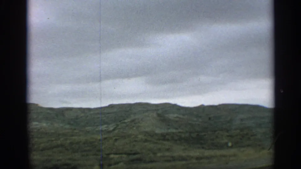 Moving 8mm view of an Arizona ridgeline, green scrub, and layered clouds during a 1959 car journey.